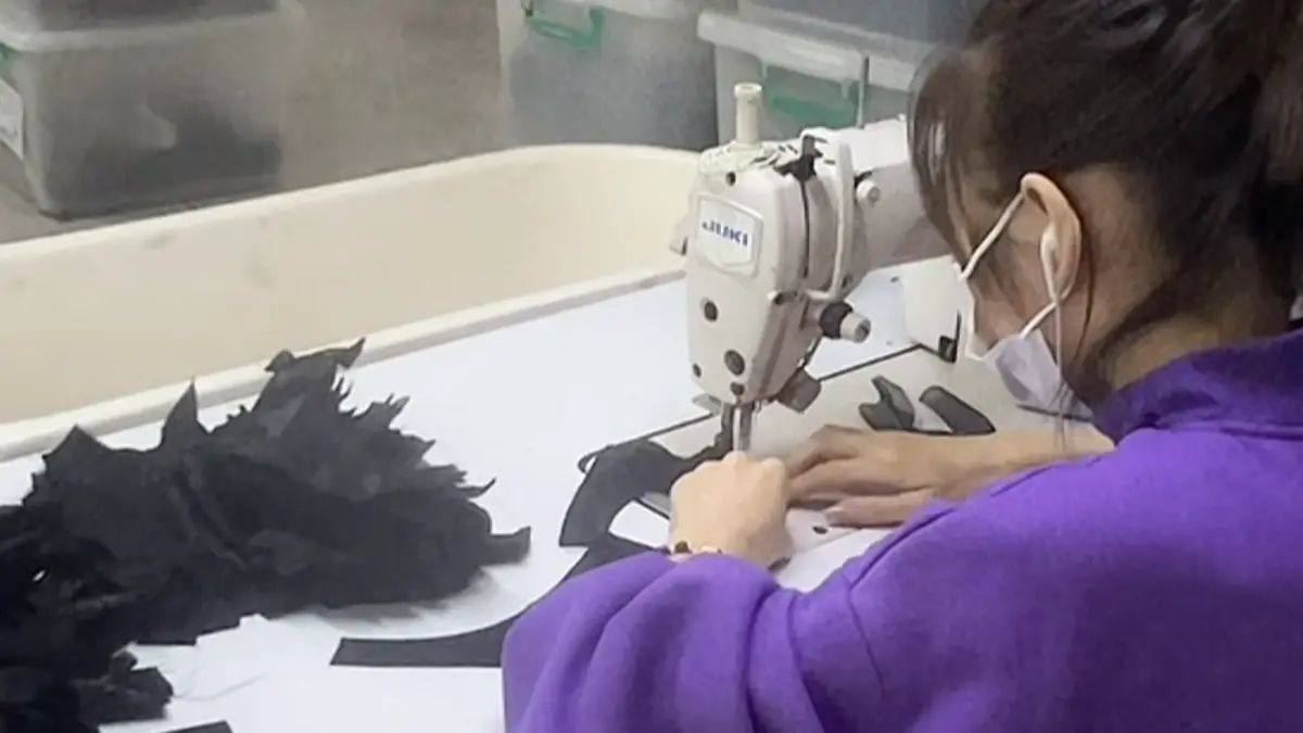 Factory worker sewing black lace lingerie fabric