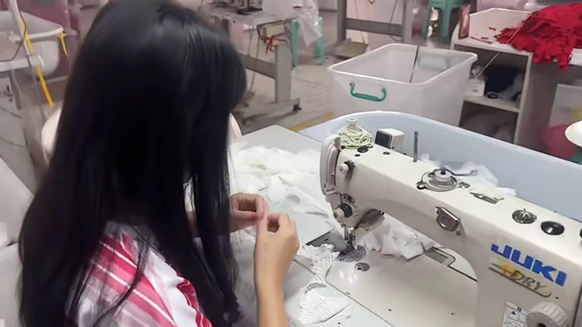 White lace bra fabric being handled at a sewing station